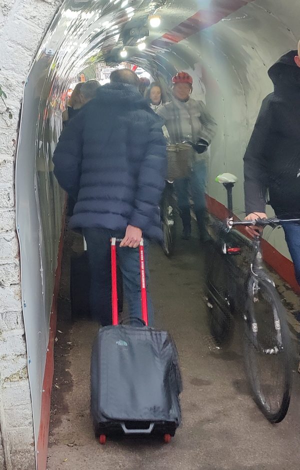 Photo of people squeezing through small tunnel while commuting to work